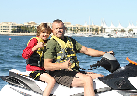A Father and Son Giving a Rock Hand Sign while on Jet Ski in Main Beach, QLD